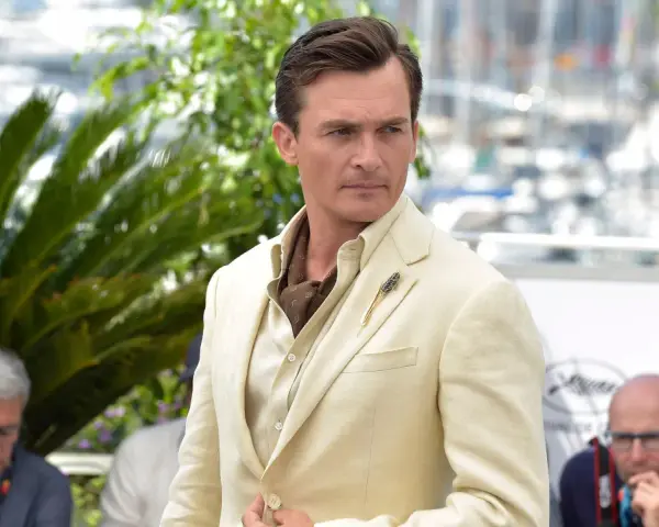 Hombre con un impecable corte de pelo old money, viste un traje de lino color crema y un pañuelo de seda.