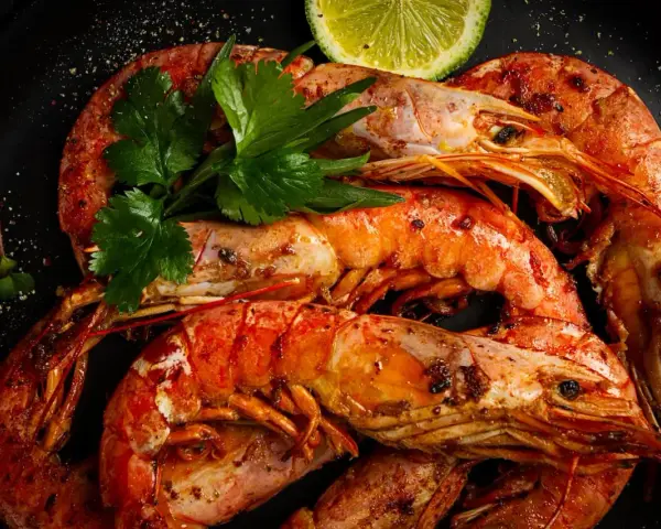 Gambones a la plancha, jugosos y dorados, servidos con perejil fresco y rodajas de lima. ¡Un manjar irresistible!