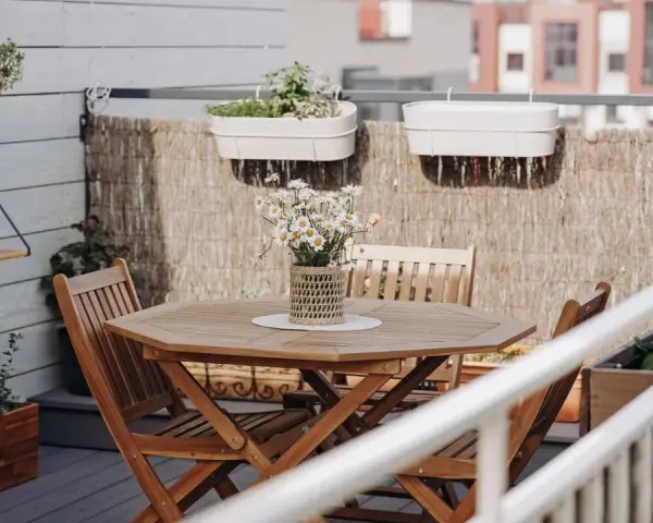 Holztisch mit Stühlen und Gänseblümchen, Wandregal mit Pflanzen, schöne Balkon Ideen für Ihr Zuhause.