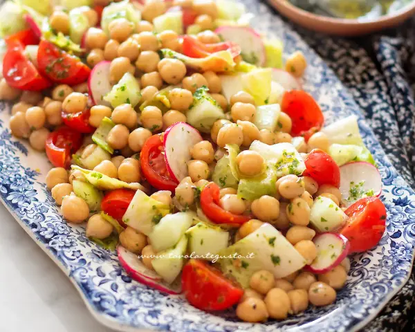 Un'insalata di legumi colorata e fresca con ceci, pomodorini, cetrioli e ravanelli, condita con erbe aromatiche.