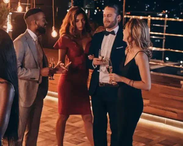 Elegante fiesta en España, cumpliendo el dress code cocktail. Hombres con traje y pajarita, mujeres con vestidos de cóctel.