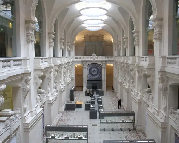 Interior del museo de artes decorativas, con arcos, balcones y vitrinas exhibiendo objetos.
