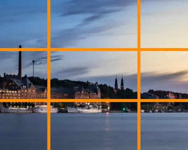 Un paysage urbain au crépuscule, avec des bâtiments historiques et des bateaux le long de l'eau. Un excellent exemple pour un tuto photographie sur la règle des tiers.