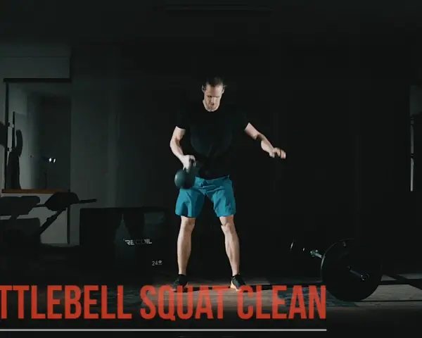 Man utför en kettlebell clean i ett mörkt gym.