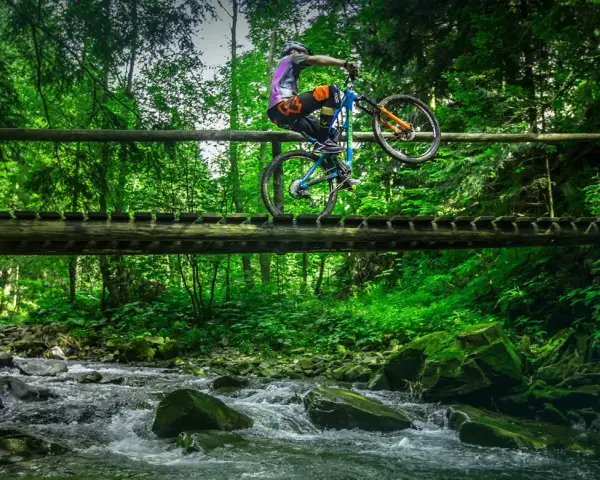 Rowerzysta na drewnianym moście nad potokiem, odkrywa nowe trasy rowerowe Zakopane.