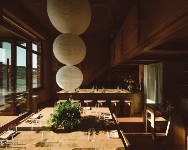 Gemütliches Restaurant in **Aerde Berlin** mit Holztischen, großen Papierlampen und Blick auf das Wasser.