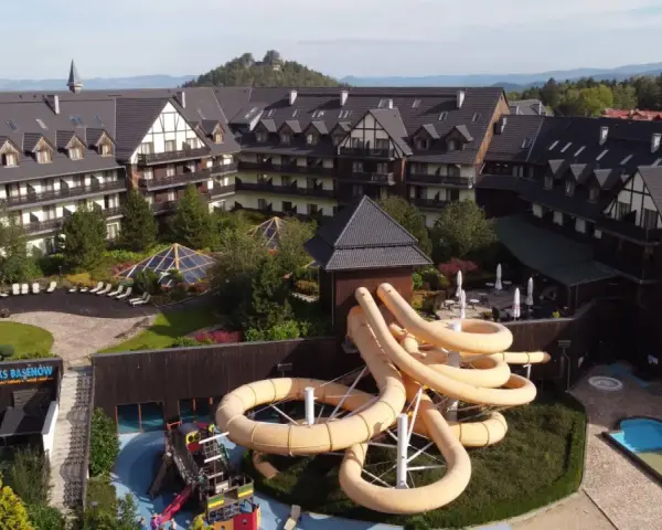 Karpacz hotel z aquaparkiem oferuje zjeżdżalnie i baseny. Widać też góry w tle.