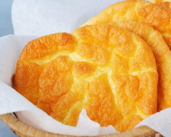 Puszyste, złociste **cloud bread** w koszyku wyłożonym papierem. Wyglądają jak chmurki!