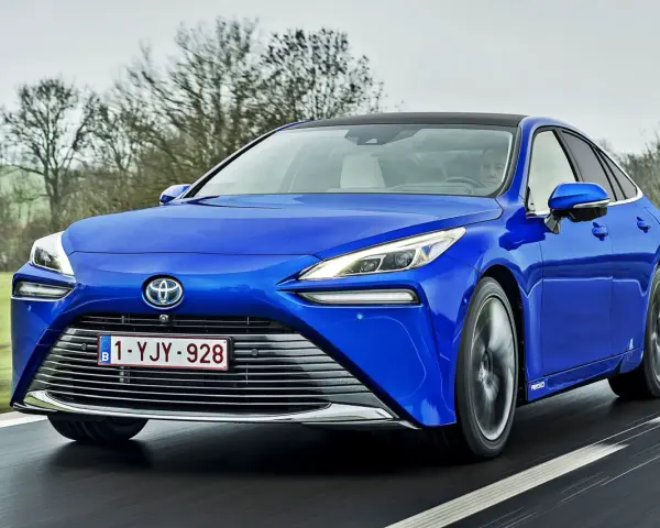 Niebieska Toyota Mirai jedzie po drodze. Sprawdź aktualną toyota mirai cena i dowiedz się więcej o tym innowacyjnym samochodzie.