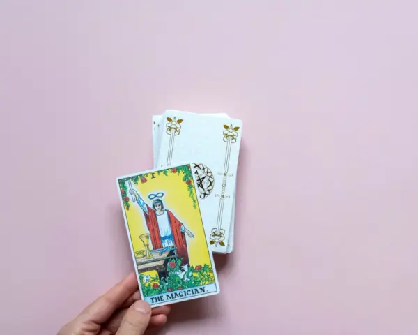 Mano sostiene la carta "El Mago" de un tarot del amor presente pasado y futuro.
