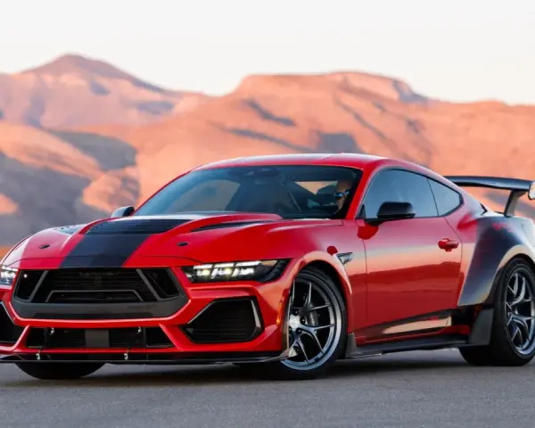Czerwony mustang shelby z czarnymi pasami i spojlerem na tle pustynnych gór.
