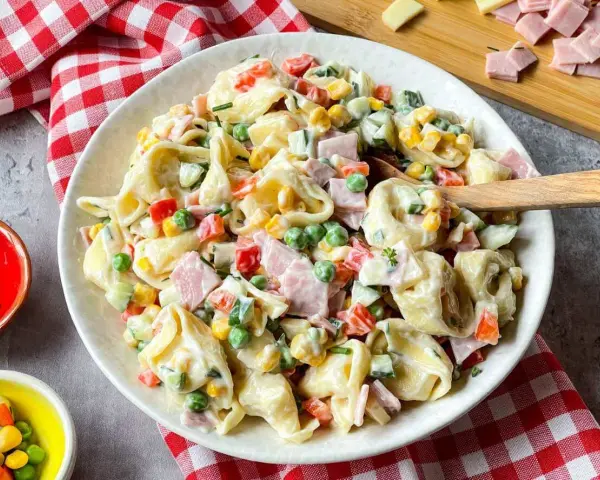 Cremiger Tortellini Salat mit Erbsen, Mais, Paprika und Schinken. Ein perfekter Sommergenuss!