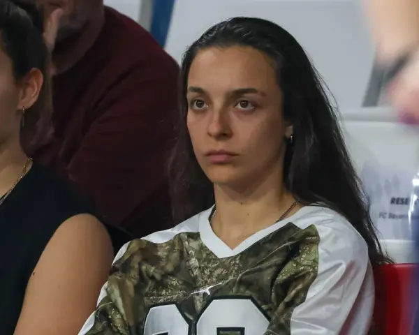 Natalia Padilla Bidas, zamyślona, siedzi na trybunach w koszulce z motywem kamuflażu.