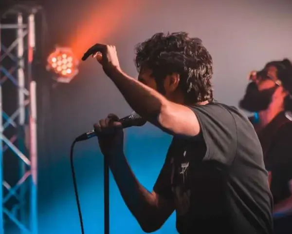 Ein Sänger mit Mikrofon auf einer Bühne, umgeben von Bühnenlichtern. Das ist, was Indie-Musik ausmacht: Leidenschaft und Energie.