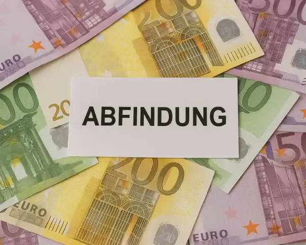 Euro-Scheine liegen unter einem Zettel mit dem Wort "Abfindung". Vielleicht eine finanzielle Unterstützung für jemanden, der mit 64 Jahren in den Ruhestand geht.