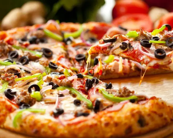 Pyszna pizza na gotowym cieście z Biedronki, z mnóstwem dodatków: mięsem, oliwkami, papryką i cebulą. Ser ciągnie się apetycznie.