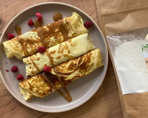 Naleśniki z malinami i syropem, obok paczka mąki bambusowej. Idealne przepisy na zdrowe śniadanie.