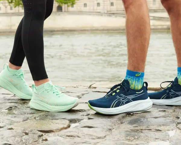 Två par löparskor, mintgröna Asics Gel Luminus 2 dam och mörkblå herrskor, står på stenar vid en flod.
