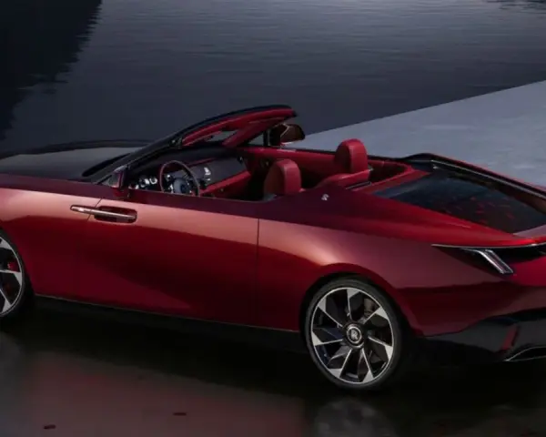 Czerwony kabriolet Rolls-Royce, najdroższe auto na świecie, lśni przy wodzie.