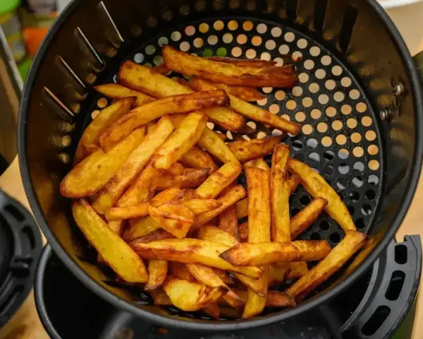 Złociste frytki w koszyku frytkownicy beztłuszczowej. Tak działa air fryer, przygotowując chrupiące przekąski.