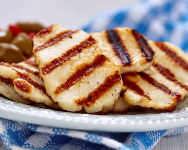 Grillowany ser halloumi na talerzu, z widocznymi paskami z grilla. Idealny dodatek do sałatek, z niską zawartością halloumi kcal.