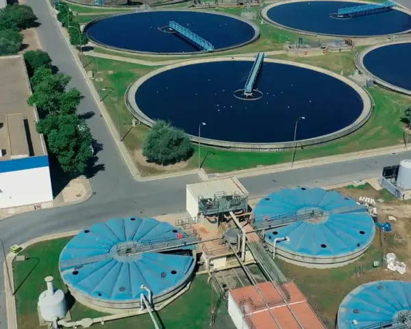 Vista aérea de una planta de depuración de aguas con grandes tanques circulares y estructuras industriales.
