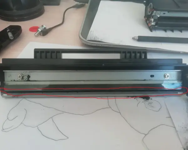 Rozłożony sp112 toner z widocznym wałkiem i resztkami proszku. Czerwona linia zaznacza uszkodzony element.