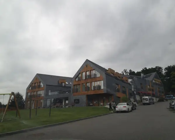 Nowoczesny hotel z drewnianymi elementami i kamienną elewacją. Na trawniku plac zabaw. Wiele pozytywnych osada-sniezka opinie potwierdza jego urok.