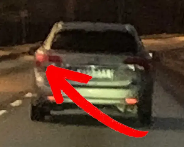 En röd pil pekar på bakljuset på en bil. Det är mörkt ute, och man undrar om man måste ha bakljus på dagen.