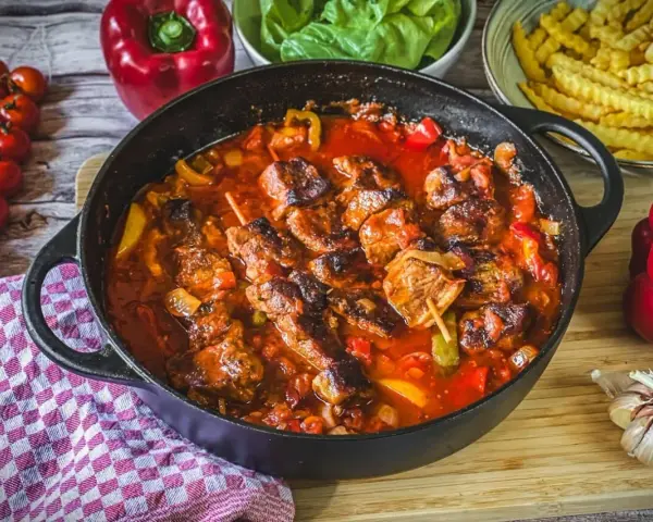 Herzhaftes Schaschlik-Rezept in Gusseisenpfanne mit Paprika, Zwiebeln und Tomaten. Dazu Pommes und frische Zutaten.