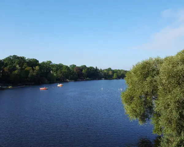 Ein ruhiger See mit Booten, umgeben von grünen Bäumen. Ein perfekter Ort für einen entspannten Tag, ein echter Geheimtipp in Berlin.