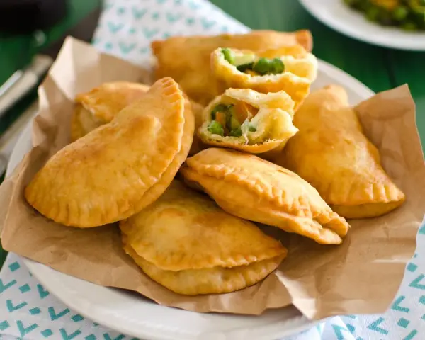 Panzerotti al forno dorati e ripieni di verdure, serviti su carta da forno.