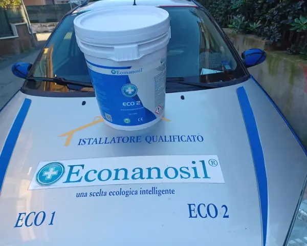 Secchio Econanosil ECO 2, 32 litri, su cofano auto con adesivi "Installatore Qualificato" e "una scelta ecologica intelligente". Scheda tecnica visibile.