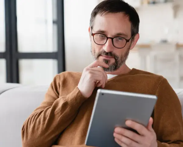 Mann sitzt nachdenklich auf Sofa, sein Samsung Tablet geht nicht mehr an.