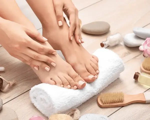 Pied sec que faire ? Mains douces caressant des pieds soignés, entourés d'accessoires de spa.
