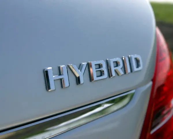 Chromowane napisy "HYBRID" na białym nadwoziu samochodu. To nowoczesny hybrydowy pojazd elektryczny, gotowy na ekologiczną podróż.