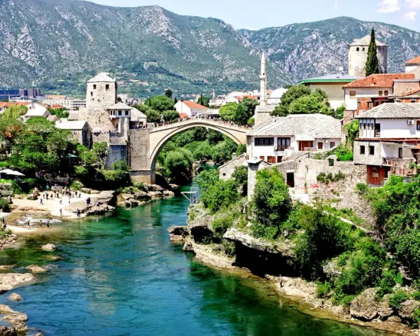 Mostar, Bośnia i Hercegowina. Tłumy ludzi spacerują po Starym Moście, a turkusowa rzeka Neretwa płynie poniżej. Czy Bośnia i Hercegowina jest bezpieczna? Tak, to piękny kraj.
