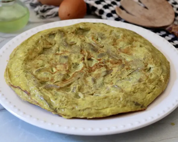 Frittata di carciofi dorata e soffice su un piatto bianco, pronta per essere gustata.