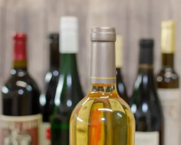 Butelki z winem na tle drewnianej ściany. Zastanawiasz się, ile alkoholu można wziąć do Norwegii samolotem?