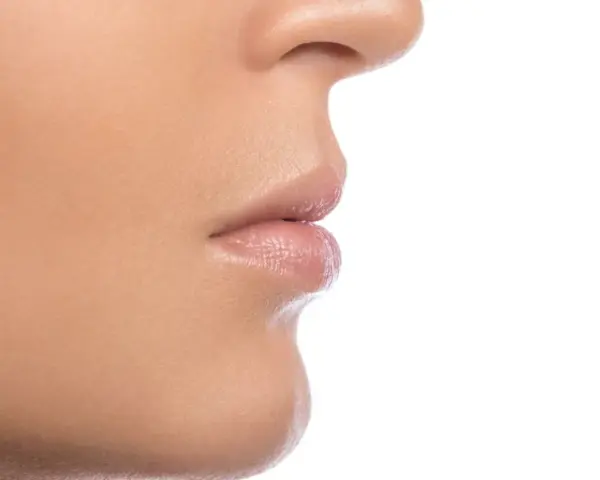 Primer plano de la nariz y los labios de una persona, mostrando la textura de la piel y los filamentos sebáceos en la nariz.