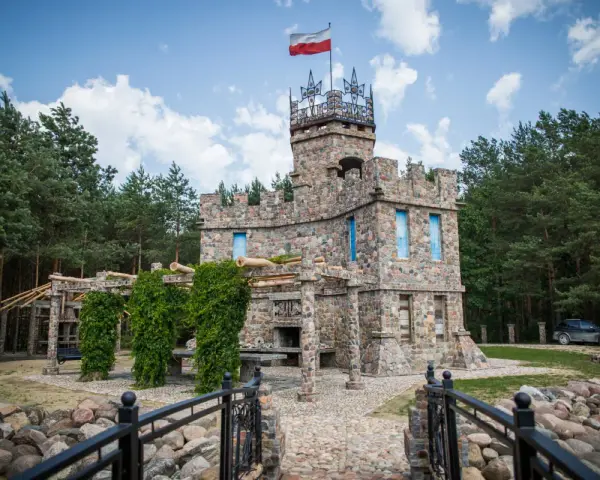 Kamienny zamek z polską flagą, otoczony lasem. Czy to właśnie tutaj jest Podlasie?