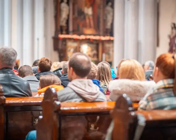 Ludzie siedzą w kościele, słuchając kazania. Wszyscy otrzymują błogosławieństwo, składając życzenia na bierzmowanie.