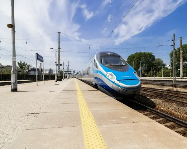Pendolino na peronie, niebiesko-srebrny pociąg, słoneczny dzień.
