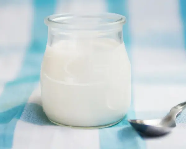 Słoiczek z domowym jogurtem, pełnym naturalnych probiotyków, czeka na łyżeczkę.