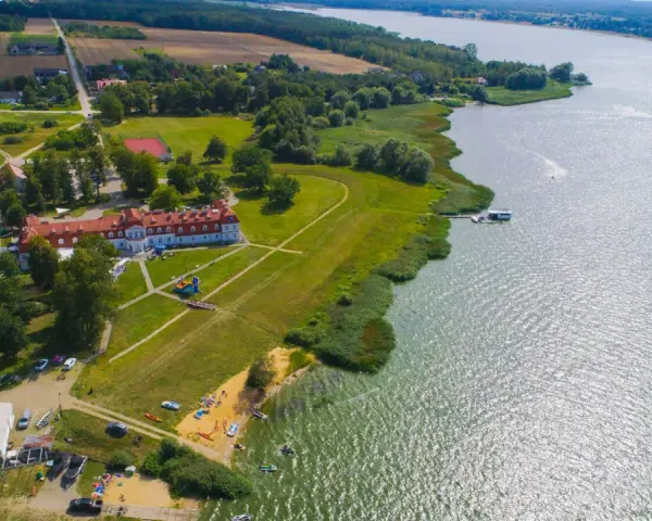 Widok z lotu ptaka na **zalew domaniow** z hotelem, plażą, kajakami i łodziami.