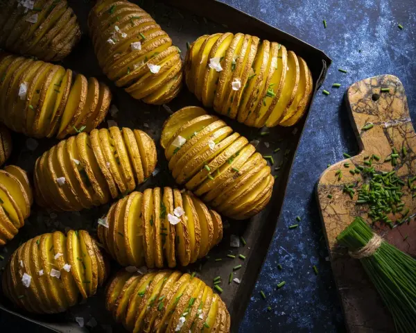 Patatas Hasselback doradas y crujientes, perfectas para tus recetas con patatas. Espolvoreadas con sal marina y cebollino fresco.