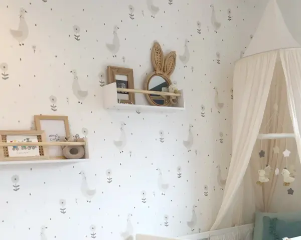 Habitaciones con papel pintado y pintura de patitos y flores. Un dosel de cama blanco cuelga sobre una cuna.