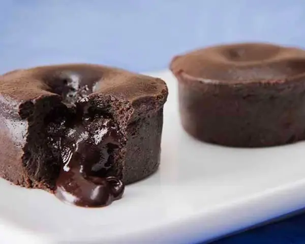 Fondant au chocolat coulant, une gourmandise inspirée de la recette de Cyril Lignac. Le cœur liquide de chocolat fond sur la plaque blanche.