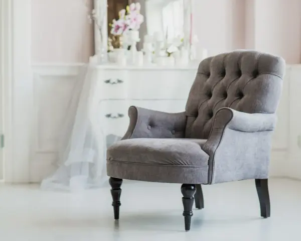 Elegante sillón gris con botones, ideal para un tocador. ¿Cuánto vale tapizar una silla así?