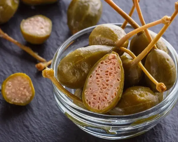 Cucunci sotto sale in una ciotola di vetro, alcuni tagliati a metà rivelano la loro polpa interna.